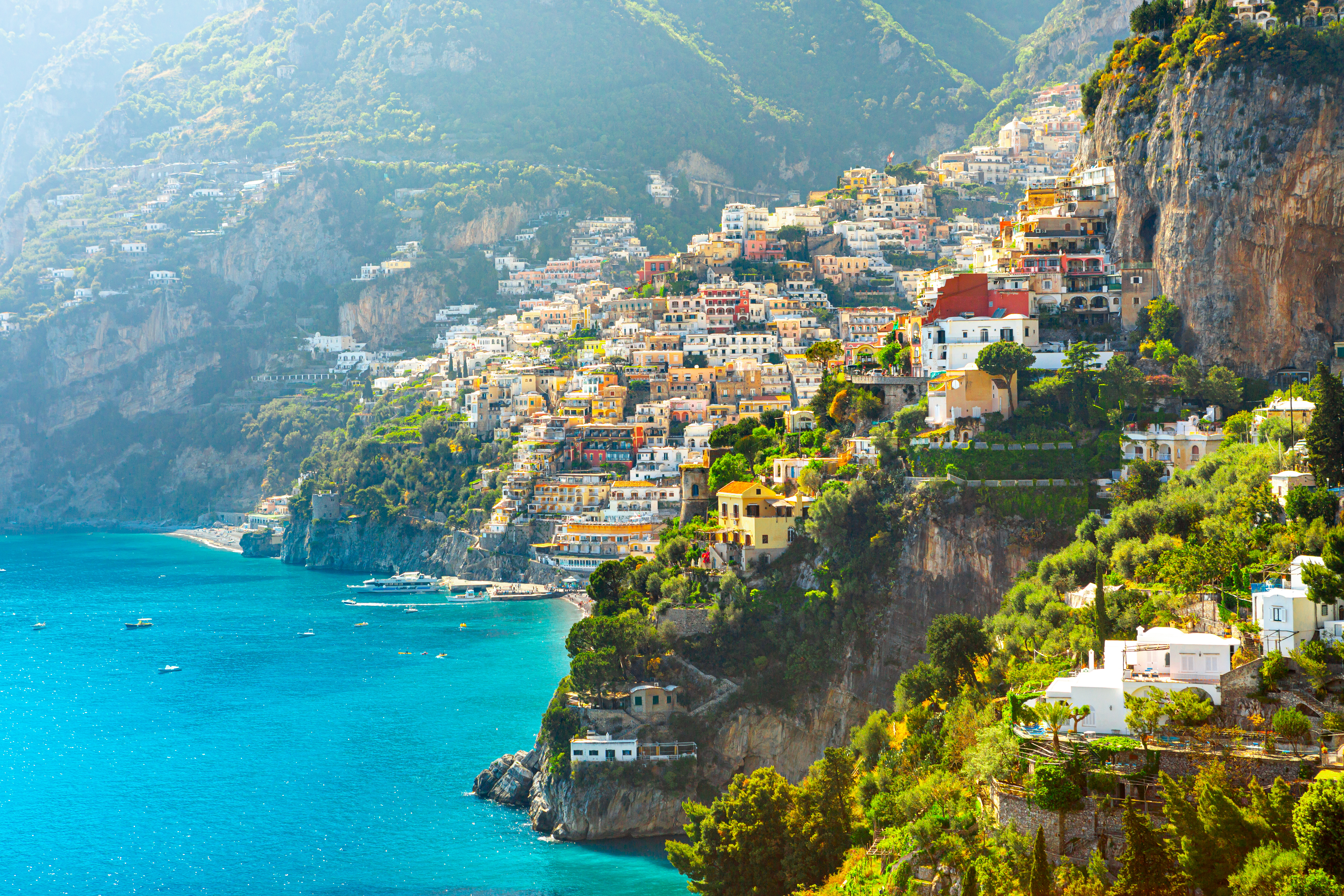 Betagende morgenudsigt over Positano på Amalfikysten med farverige bygninger der kaskader ned ad klippen til det azurblå Middelhav i Italien