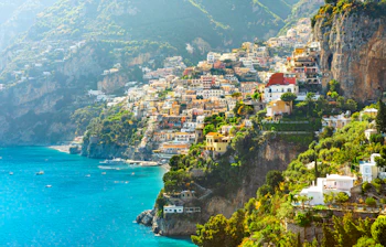 Betagende morgenudsigt over Positano på Amalfikysten med farverige bygninger der kaskader ned ad klippen til det azurblå Middelhav i Italien