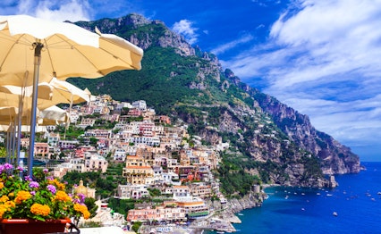 Betagende panoramaudsigt over Positano på Amalfikysten med farverige bygninger, der falder ned mod det turkisblå Middelhav, perfekt eksempel på luksuriøse italienske kystferier