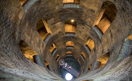 Fascinerende indvendig udsigt af den historiske brønd Pozzo di San Patrizio i Orvieto, der viser den geniale dobbelte spiraltrappe-konstruktion med naturligt lys, der strømmer ind gennem vinduerne i dette renæssance-mesterværk