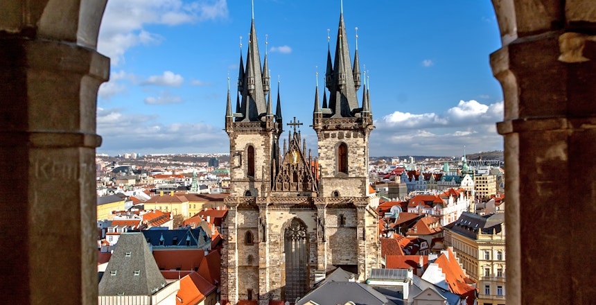 Udsigt over Prags Gamle Torv med Tyn Kirkes tårne set gennem gotisk stenbue