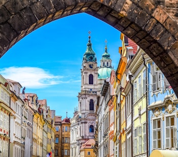 Historisk Prag set gennem stenbue med barokkirke og farverige bygninger i gamlebyen