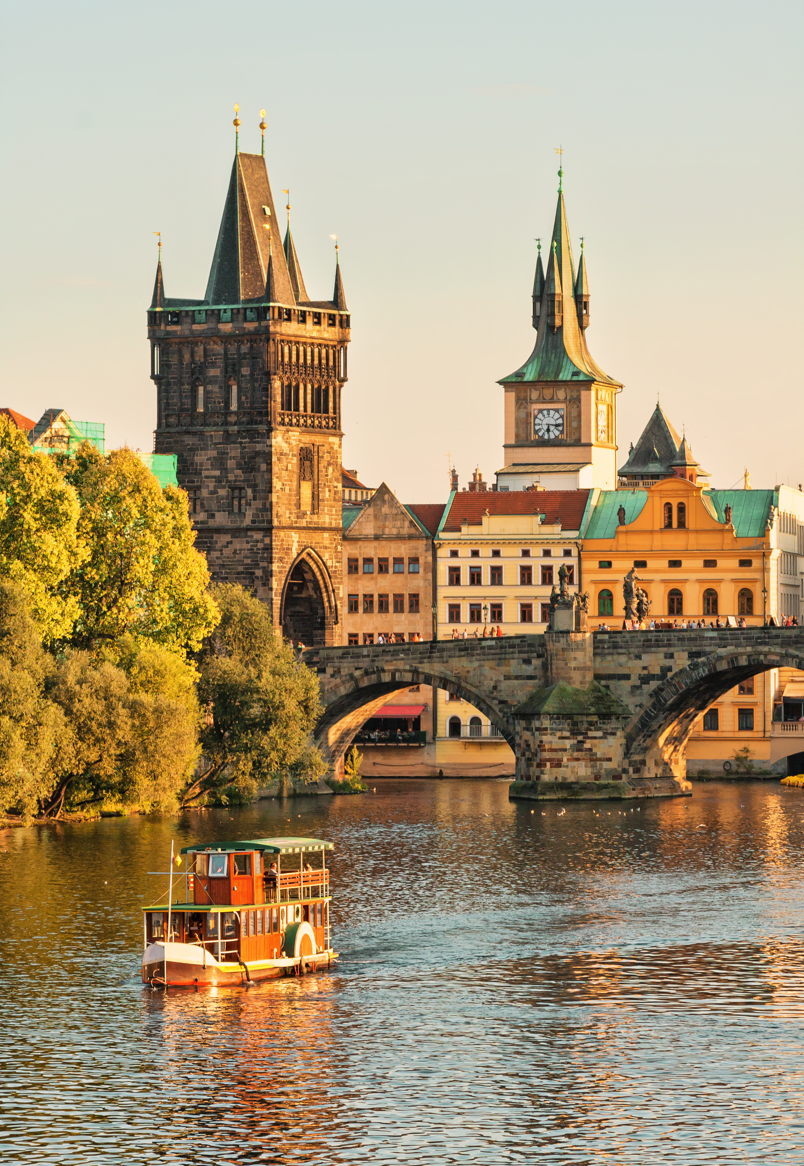 Historiske Charles Bridge med middelalderlige taarne og turistbaad paa Vltava floden i Praha Tjekkiet