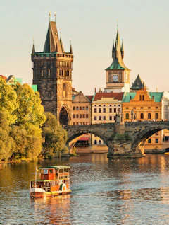 Historiske Charles Bridge med middelalderlige taarne og turistbaad paa Vltava floden i Praha Tjekkiet