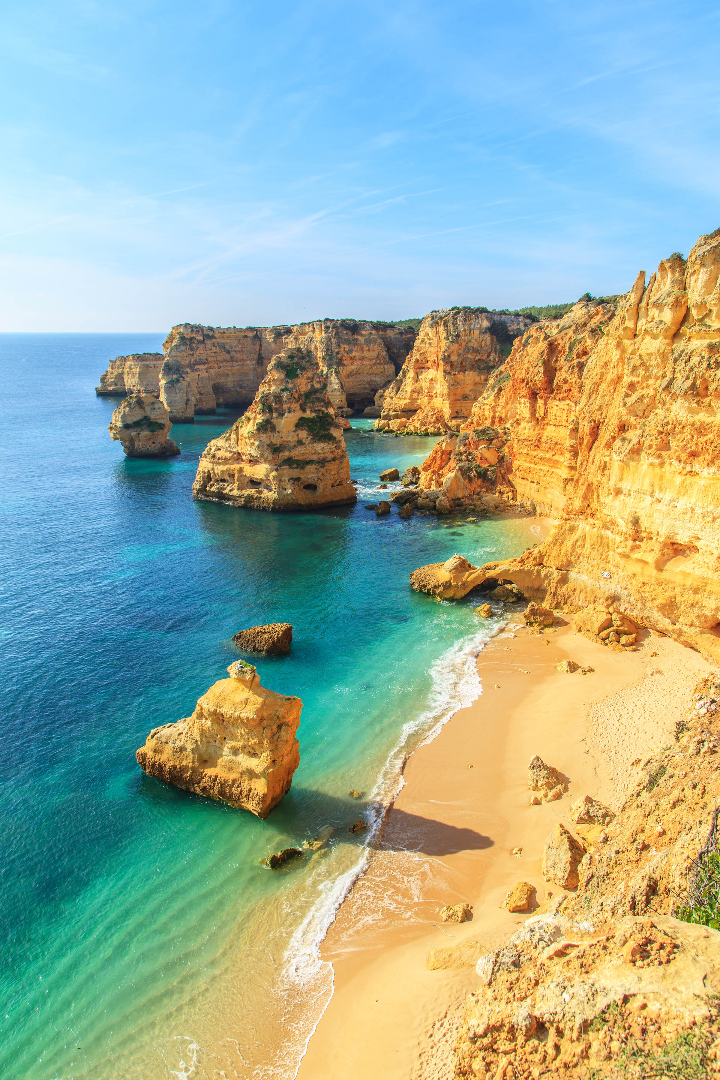 Betagende udsigt over Praia da Rocha stranden i Portimao med gyldent sand, turkisblåt vand og majestætiske kalkstensklipper langs Algarves smukke kystlinje