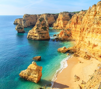Betagende udsigt over Praia da Rocha stranden i Portimao med gyldent sand, turkisblåt vand og majestætiske kalkstensklipper langs Algarves smukke kystlinje