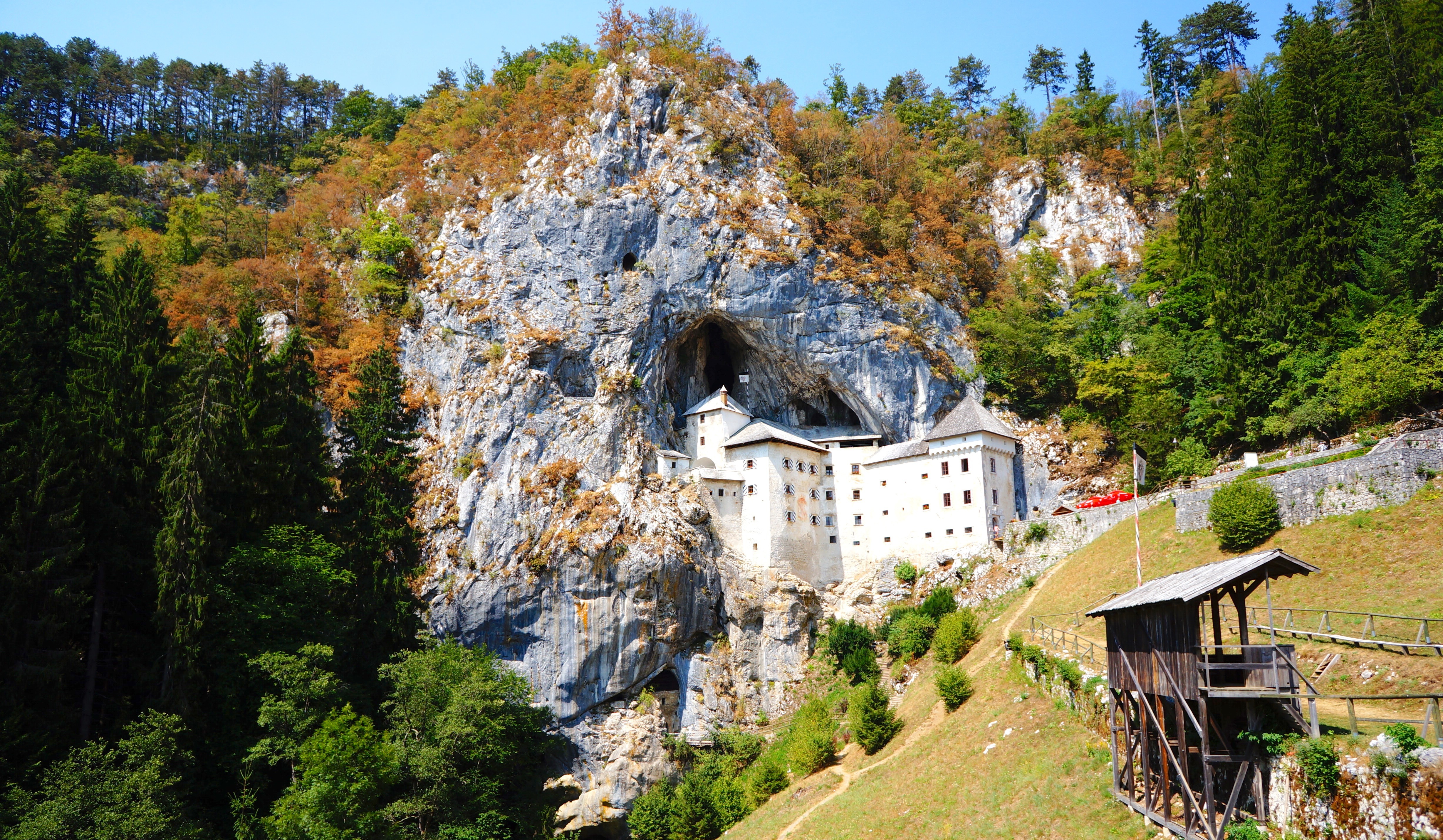 Predjama Slot i Slovenien - Unikt renæssanceslot bygget ind i en huleside nær Postojna, omgivet af grøn skov og stejle klippevægge