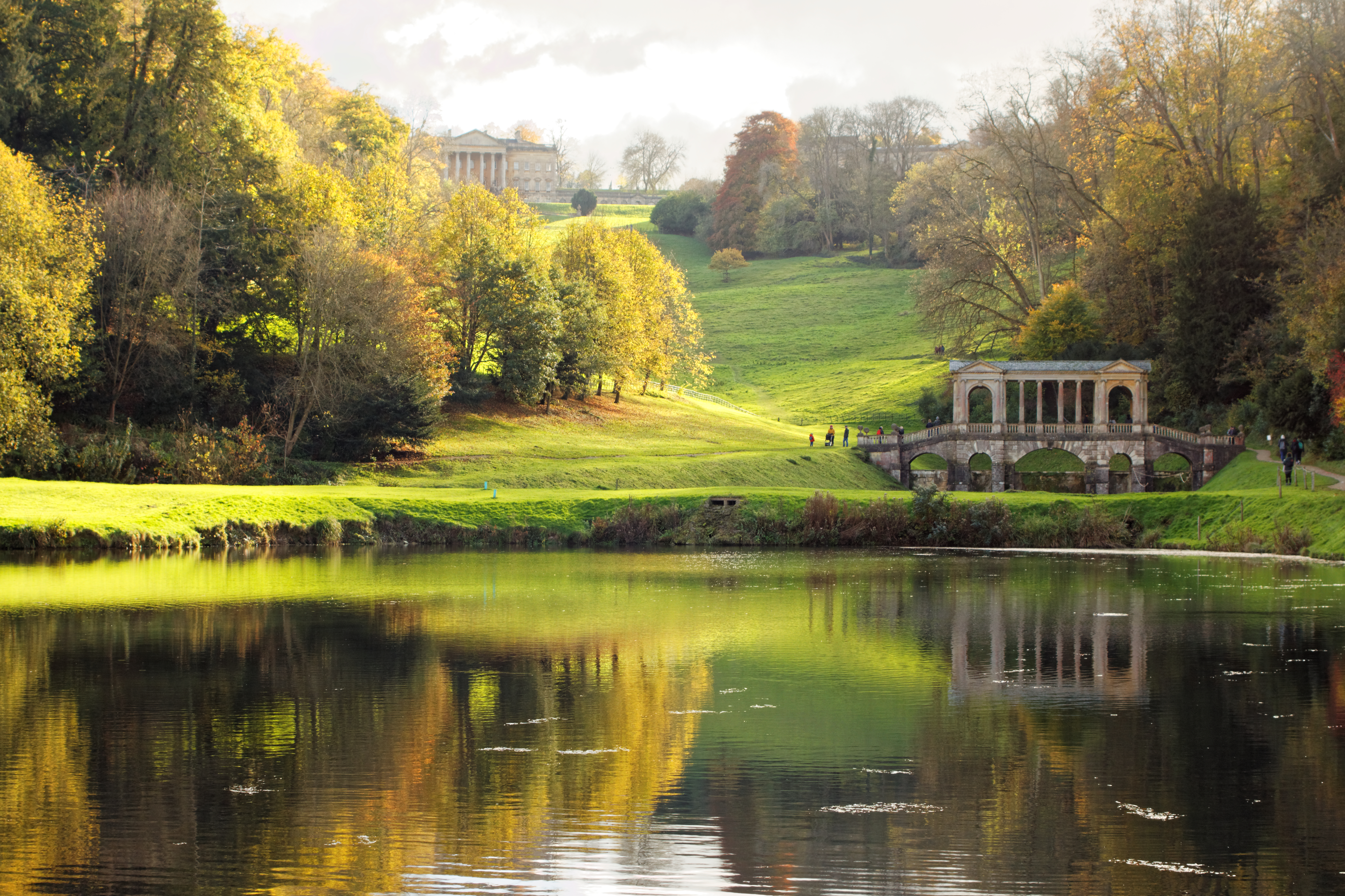 Historisk stenbro omgivet af farverige efterårstræer i Prior Park Landscape Garden nær Bath i England