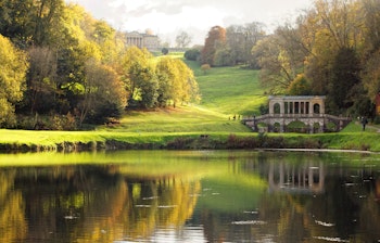 Historisk stenbro omgivet af farverige efterårstræer i Prior Park Landscape Garden nær Bath i England