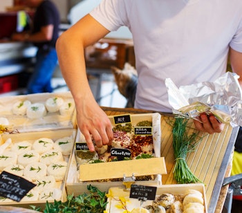 Lokal ostesælger på farverigt marked i Provence, Frankrig med traditionelle franske oste