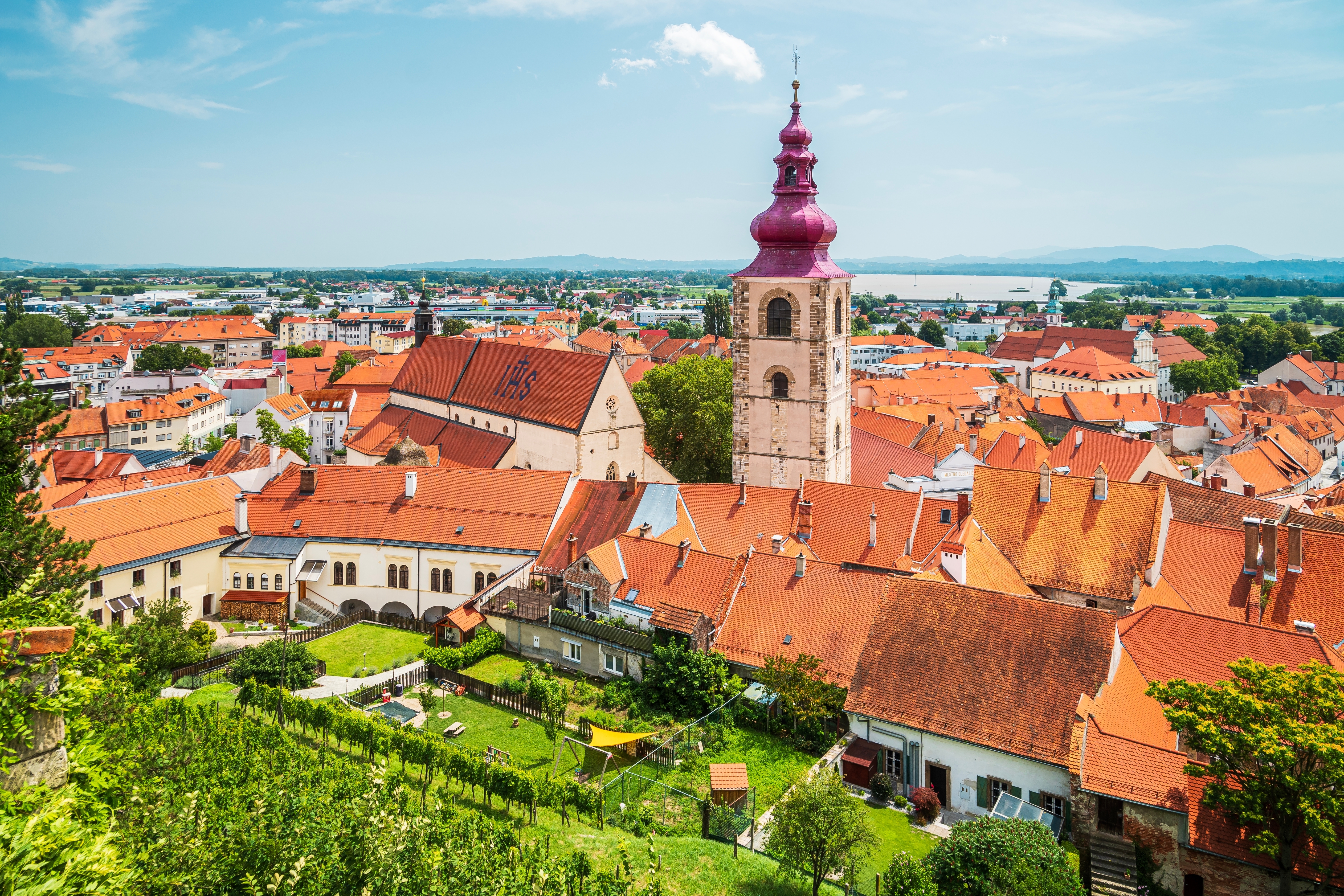 Luftfoto af Ptuj i Slovenien med historisk kirketårn og røde tegltagе