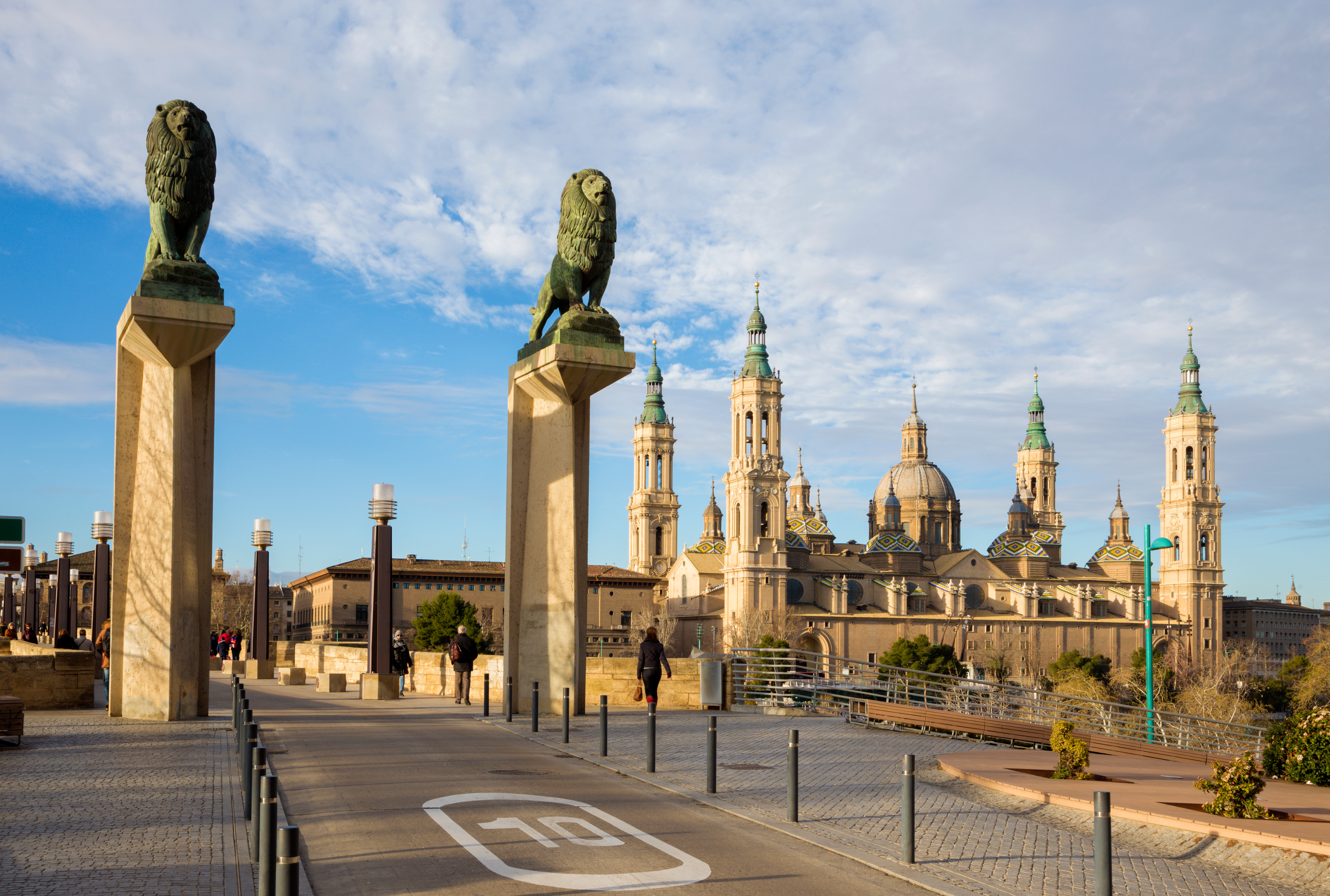 Den historiske Puente de Piedra (Stenbroen) også kendt som Løvebroen, der krydser Ebro-floden i Zaragoza med den imponerende Basilica del Pilar i baggrunden, badet i gyldent morgenlys