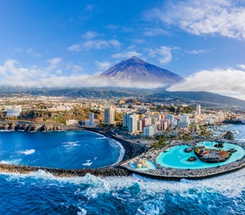 Betagende luftfoto af Puerto de la Cruz kystby med Teide vulkanen i baggrunden på Tenerife, De Kanariske Øer
