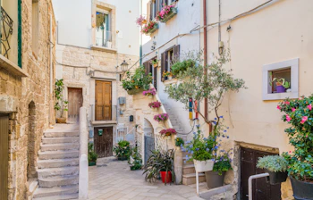 Traditionel italiensk landsby med hvide stenhuse og farverige blomster i Puglia
