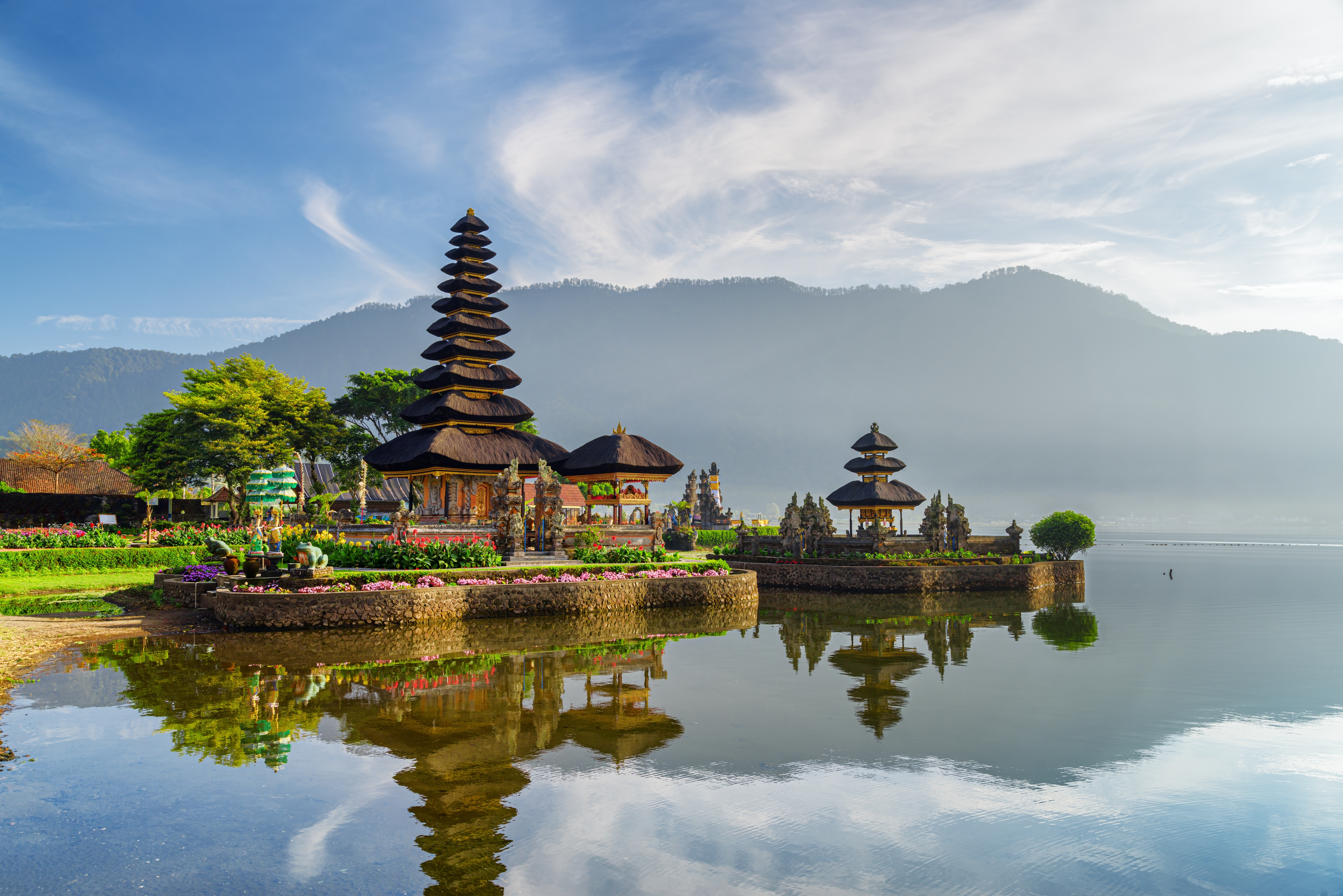 Betagende udsigt over Pura Ulun Danu Beratan templet spejlet i Beratan-søen med bjerglandskab i baggrunden, et helligt hinduistisk tempel på Bali