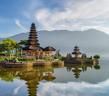 Betagende udsigt over Pura Ulun Danu Beratan templet spejlet i Beratan-søen med bjerglandskab i baggrunden, et helligt hinduistisk tempel på Bali
