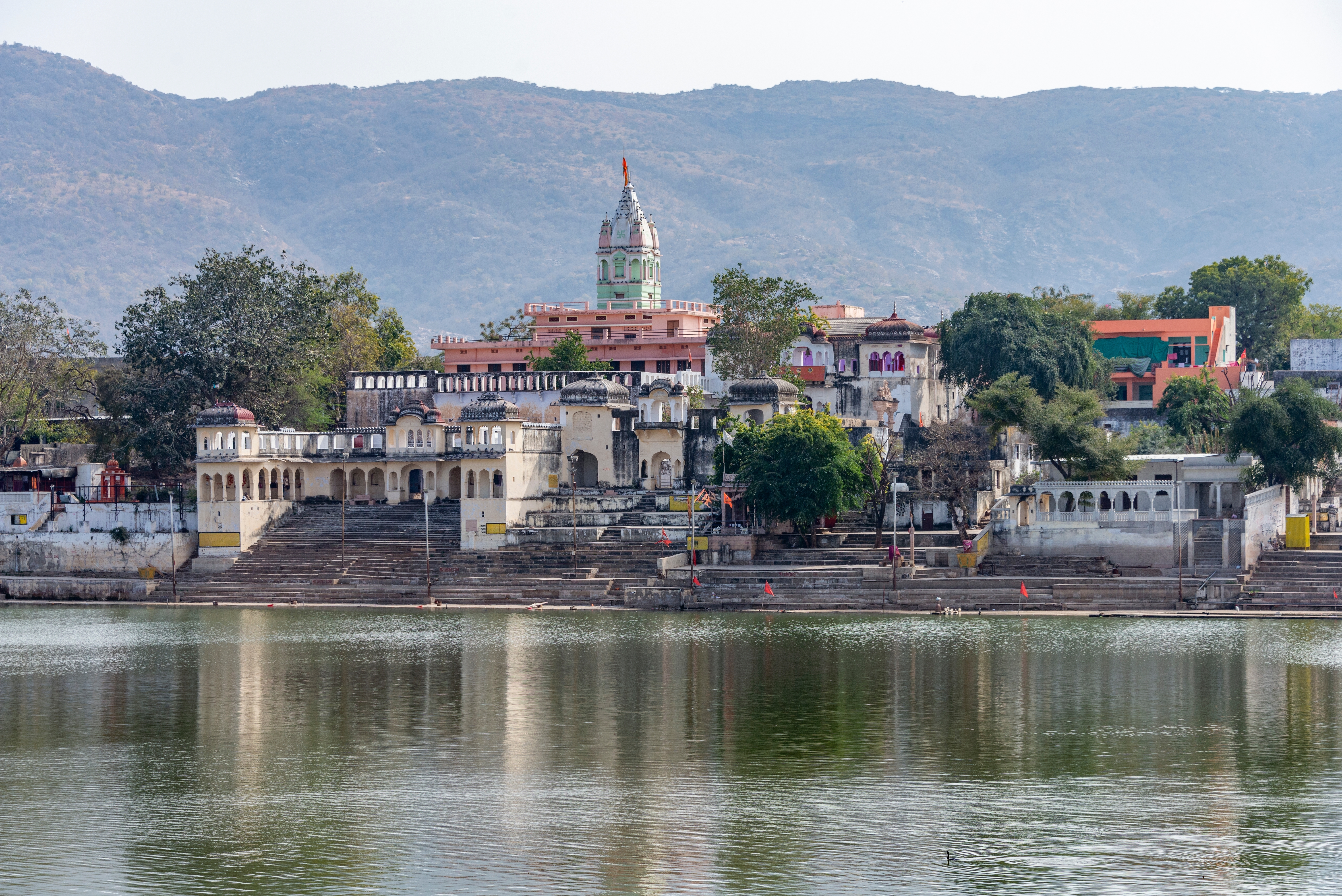 Betagende panoramaudsigt over den hellige Pushkar-sø omgivet af historiske templer og farverige bygninger i pilgrimsbyen Pushkar, Rajasthan