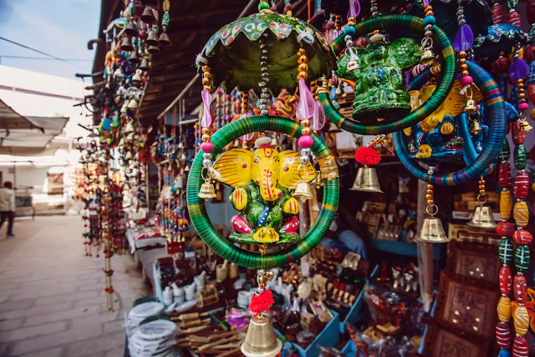 Farverig gadebutik i Pushkar med traditionelle indiske tekstiler, tørklæder og håndlavede souvenirs hængende fra indgangen