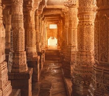 Smukt udskårne søjler med detaljerede basrelieffer i det historiske Jain-tempel i Ranakpur, Rajasthan, Indien