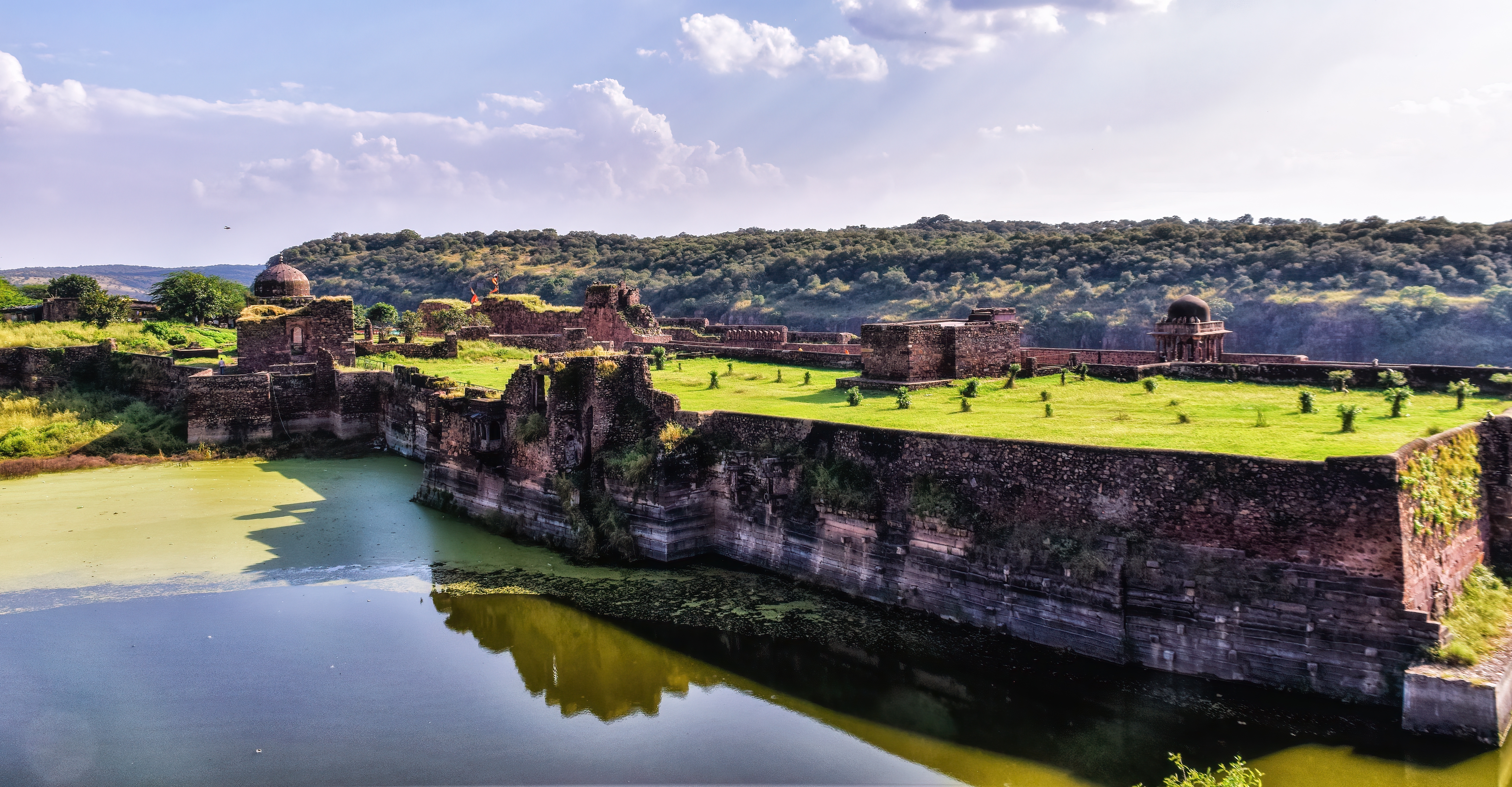 Gamle fæstningsruiner ved Ranthambore Nationalpark i Indien med grønne landskaber og vandrefleksion