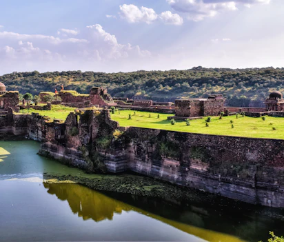 Gamle fæstningsruiner ved Ranthambore Nationalpark i Indien med grønne landskaber og vandrefleksion