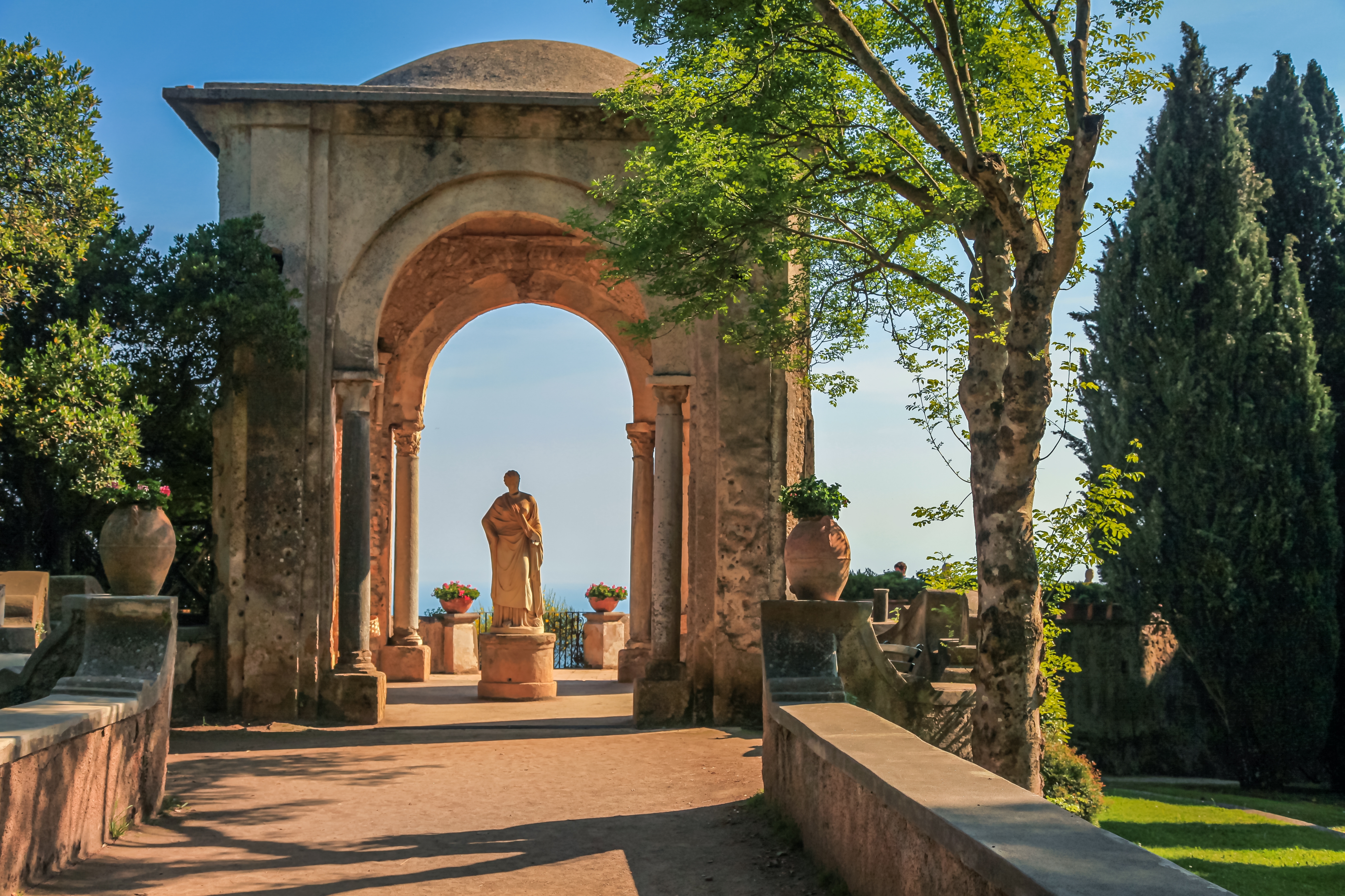 Idylliske haver i Ravello med veltrimmede blomsterbede, klassiske statuer og en betagende panoramaudsigt over Amalfikysten og det blå Tyrrhenske Hav i Campania, Italien