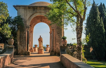 Idylliske haver i Ravello med veltrimmede blomsterbede, klassiske statuer og en betagende panoramaudsigt over Amalfikysten og det blå Tyrrhenske Hav i Campania, Italien