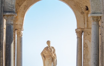Betagende udsigt fra en historisk søjlegang med statue i Ravello på Amalfikysten i Italien