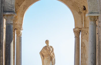 Betagende udsigt fra en historisk søjlegang med statue i Ravello på Amalfikysten i Italien