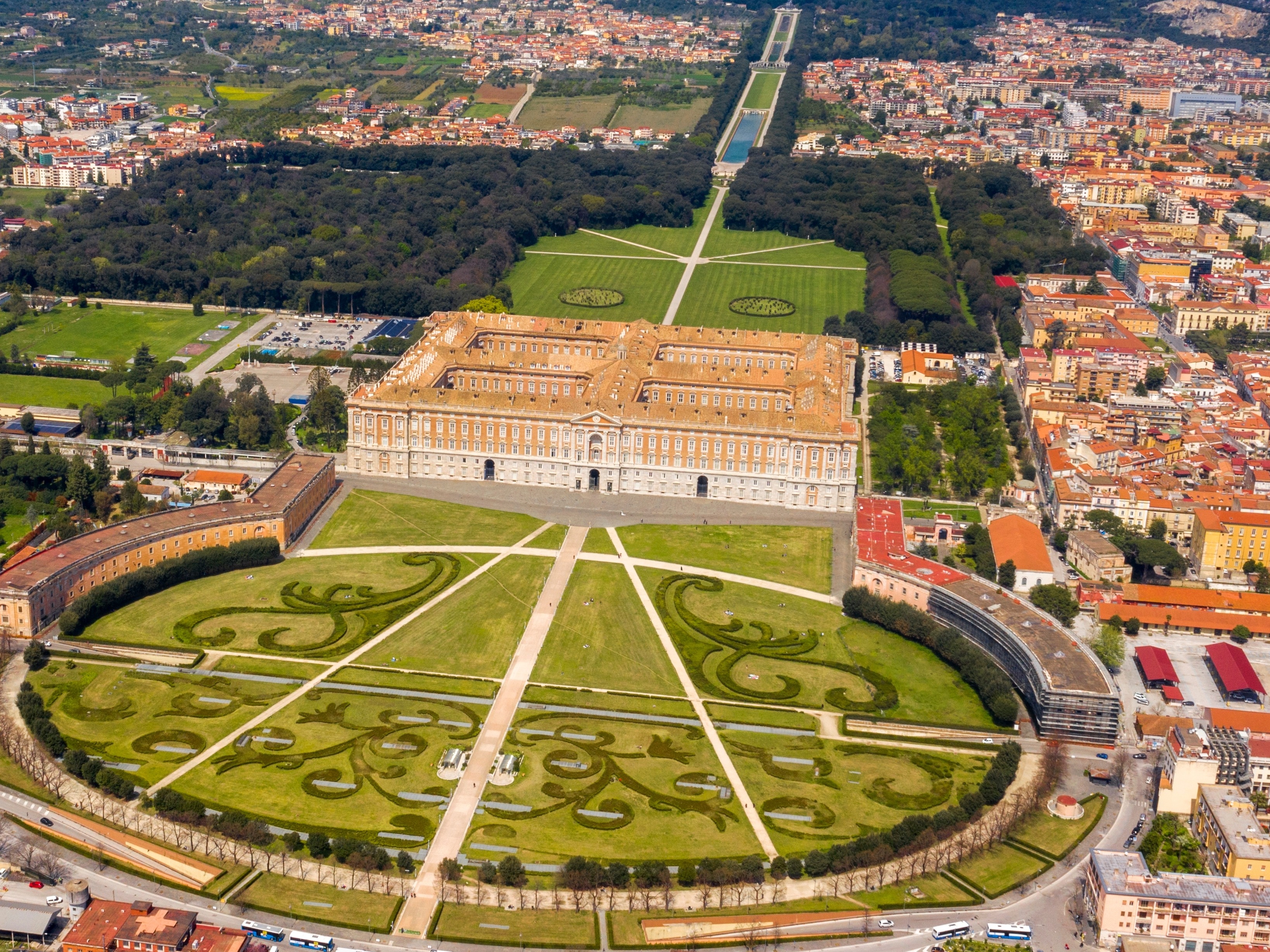 Luftfoto af det kongelige slot Reggia di Caserta med pragtfulde barokhaver og den historiske bymidte i Caserta nær Napoli, Italien