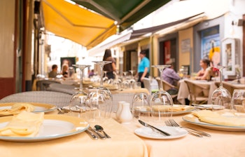 Udendørs spisning på restaurant i Funchals historiske centrum på Madeira med gule duge og charmerende gadeudsigt