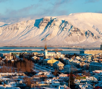 Panoramaudsigt over Reykjavik om vinteren med snedækkede tage, farverige bygninger og den ikoniske Hallgrímskirkja, der rejser sig over Islands hovedstad