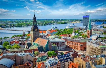 Panoramaudsigt over Rigas gamle bydel med historisk arkitektur, domkirke og Daugava-floden under blå himmel i Letland