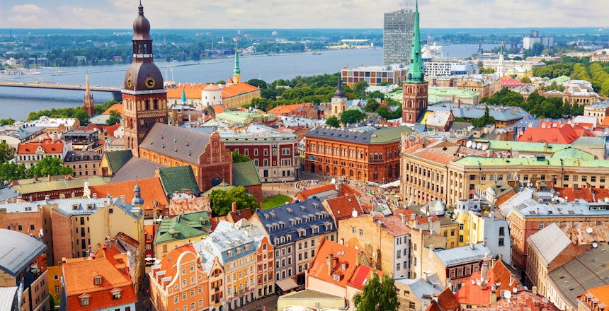 Betagende panoramaudsigt over Rigas historiske centrum med røde tegltage og kirkespir, fotograferet fra Skt. Peters Kirkes tårn på en solrig sommerdag i Letland