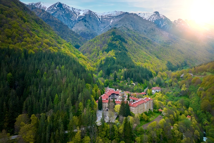 Historiske Rila Kloster i grønne bulgarske bjerge med sne-dækkede toppe og forårs skov