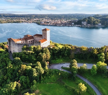 Luftfoto af den historiske Rocca Borromea fæstning med udsigt over Maggiore-søen og Arona by i baggrunden, Angera, Lombardiet, Italien