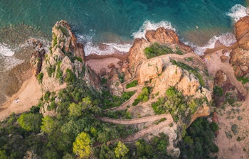 De dramatiske røde klipper ved Esterel kysten nær Theoule sur Mer på den franske riviera med azurblåt Middelhav