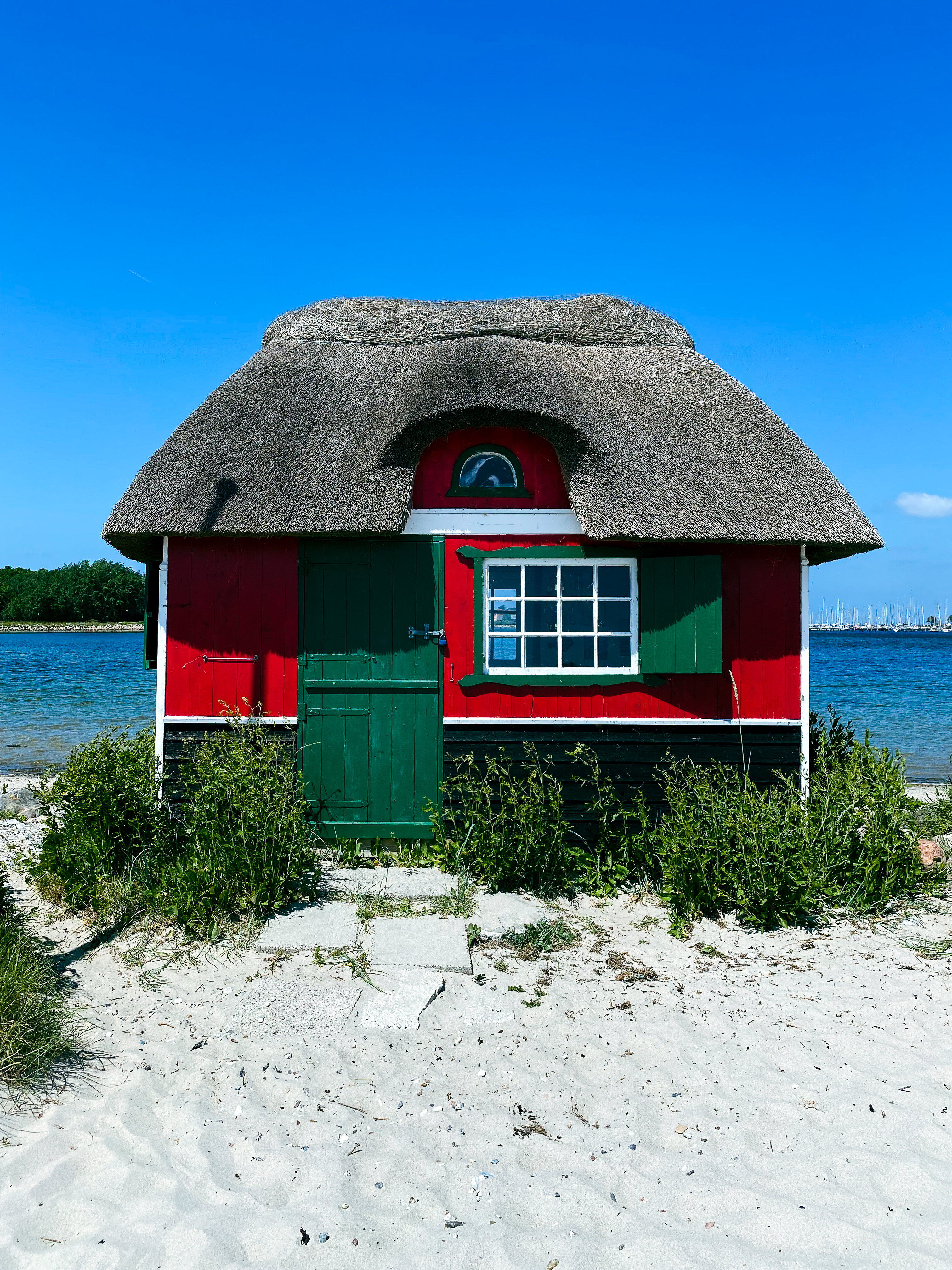 Idyllisk rødt strandhus med stråtag på den sandede kyst af Ærø, perfekt til en afslappende dansk øferie