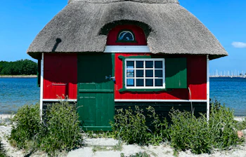 Idyllisk rødt strandhus med stråtag på den sandede kyst af Ærø, perfekt til en afslappende dansk øferie