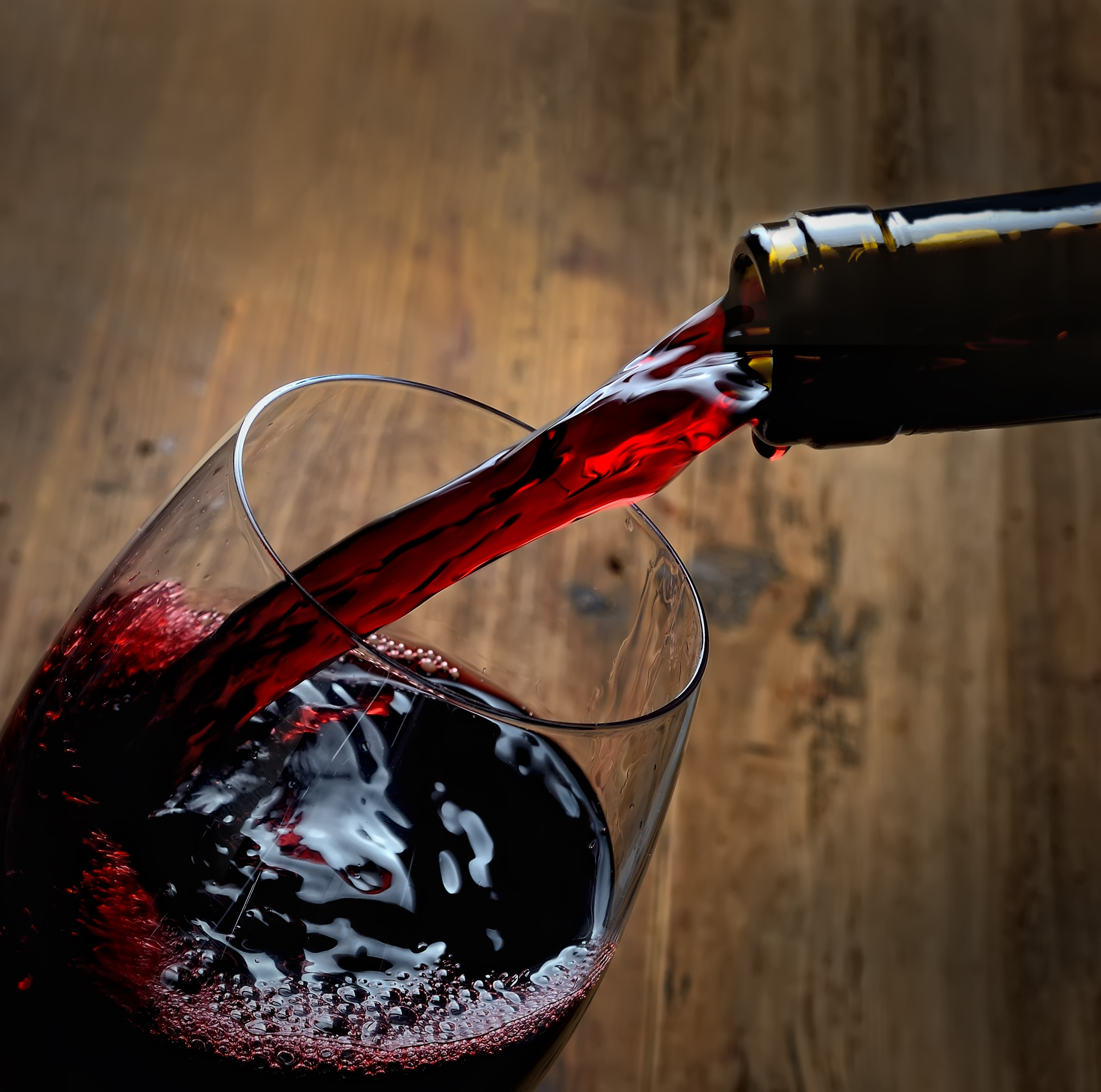 Rød vin hældes i glas på rustik træbaggrund