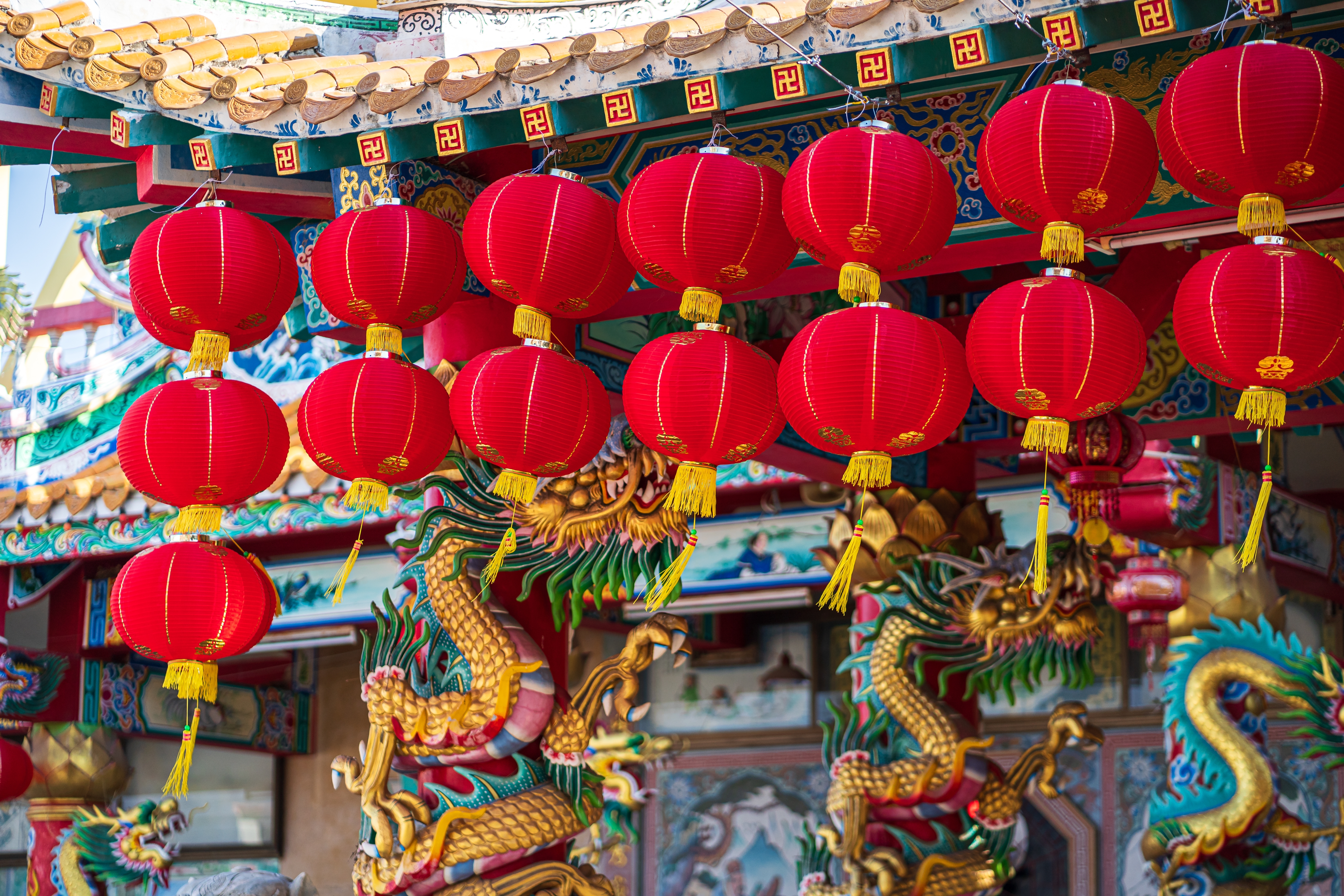 Røde kinesiske nytårslygter hænger ved traditionelt tempel med guldne drager
