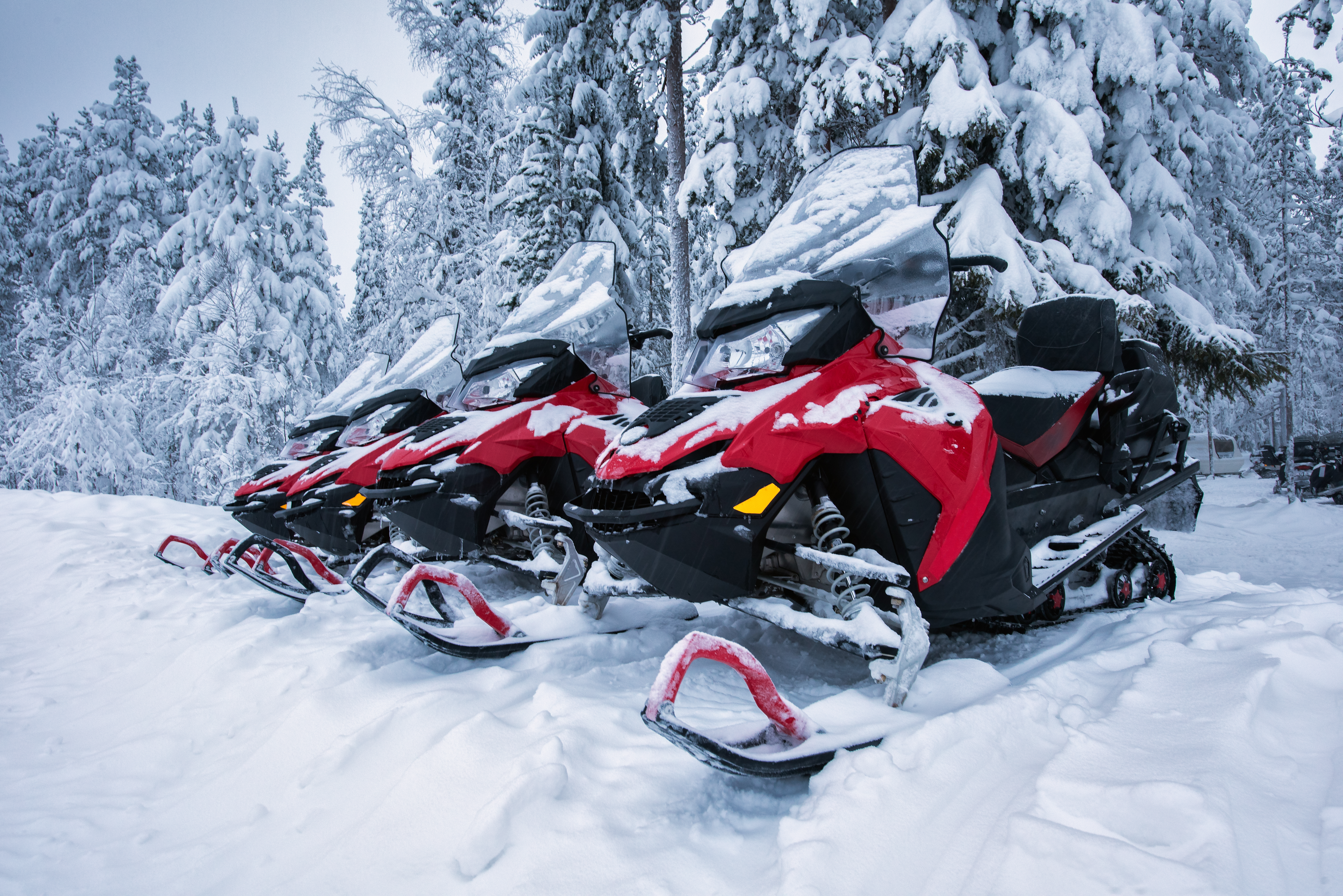 Røde snescootere parkeret i snevejr klar til vinteräventyr i Lapland
