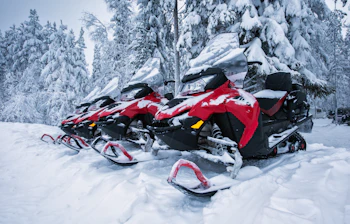 Røde snescootere parkeret i snevejr klar til vinteräventyr i Lapland