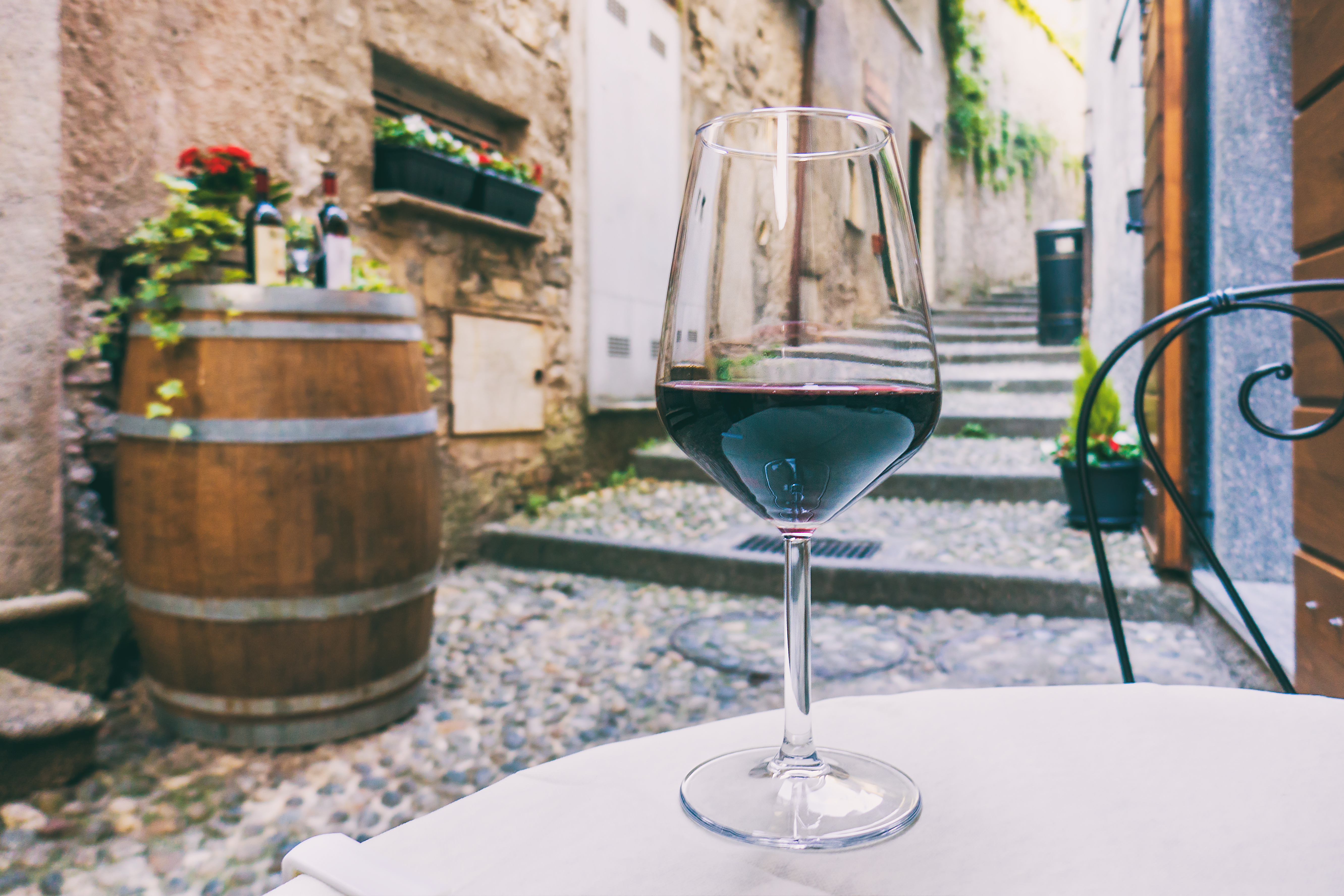 Glas rødvin på restaurantbord i charmerende italiensk brostensstræde