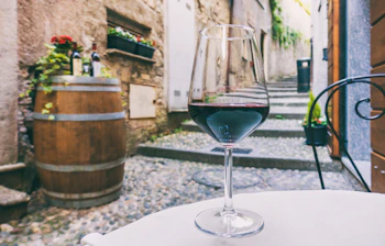 Glas rødvin på restaurantbord i charmerende italiensk brostensstræde