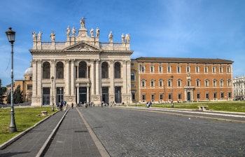 Imponerende facade af San Giovanni in Laterano basilika i Rom med dens majestætiske søjler, statuer og den store plads foran denne historiske kirke