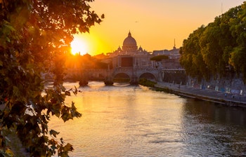 Betagende solnedgang over Peterskirken, Sant'Angelo-broen og Tiberen i Rom, Italien - et ikonisk bylandskab med historisk arkitektur