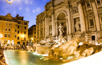 Den berømte Trevi-fontæne i Rom oplyst i aftentimerne med smukke barokke statuer og rindende vand