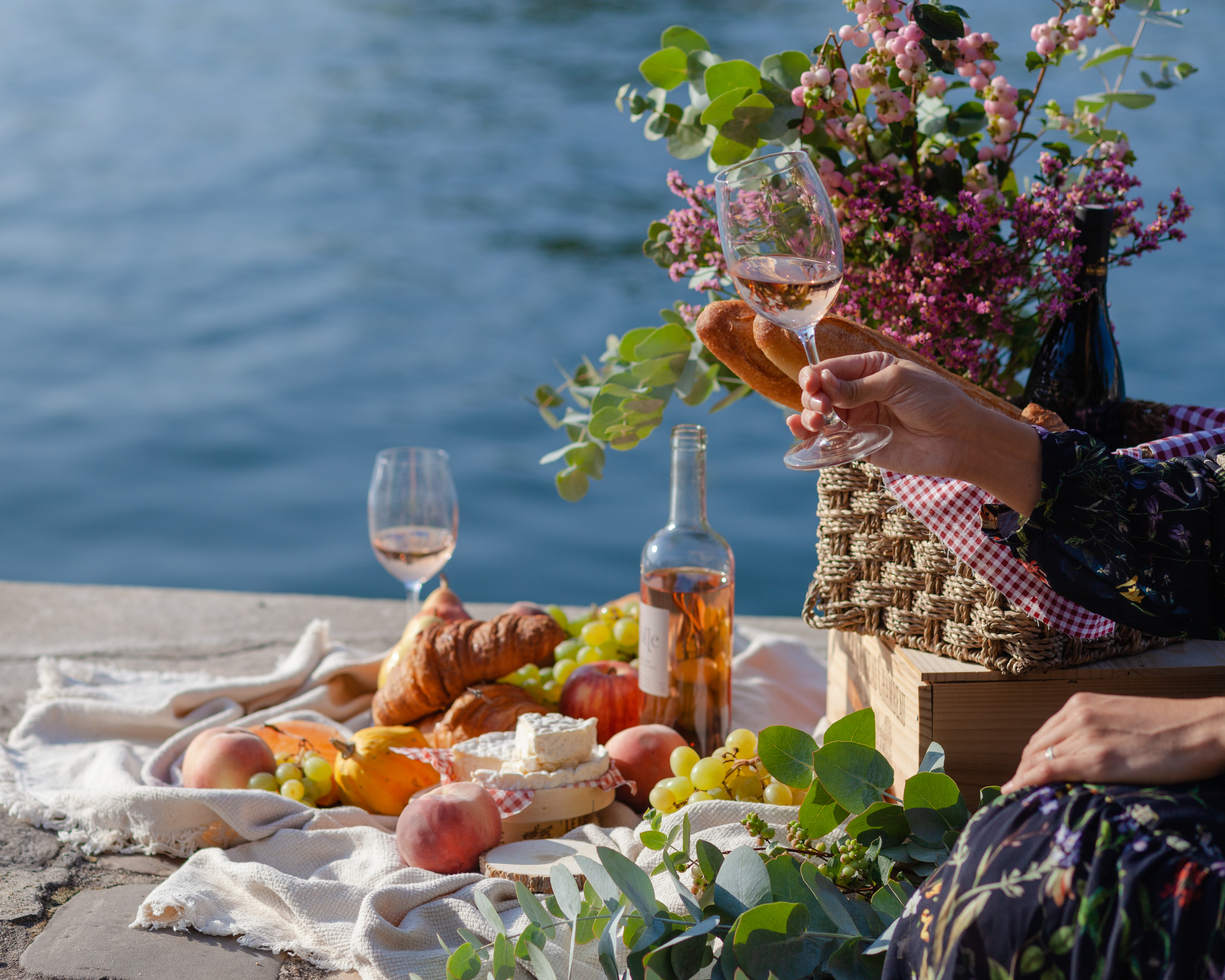 Romantisk picnic med vin, ost og croissanter ved Seinen i Paris, der viser det autentiske franske køkken og parisisk elegance