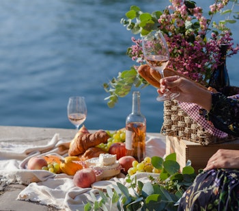 Romantisk picnic med vin, ost og croissanter ved Seinen i Paris, der viser det autentiske franske køkken og parisisk elegance